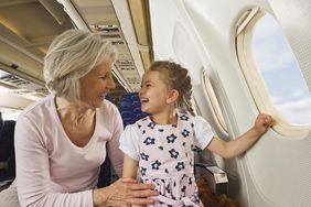 Grandparent and grandchild laughing while sitting on an airplane