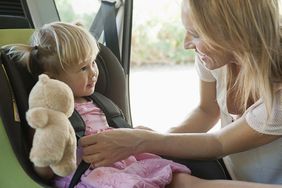 Parent fastening toddler into car seat