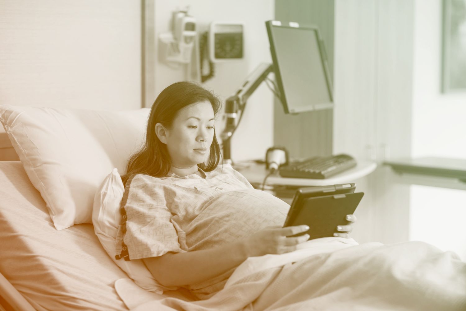 pregnant woman in hospital bed using tablet