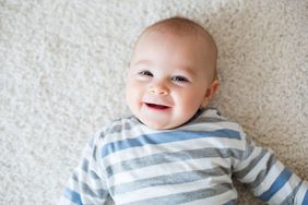 Baby boy laying on carpet.