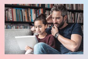 Father and daughter at sofa with digital tablet