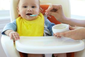 Baby Eating Infant Cereal In High Chair