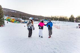 Kids walking while carrying skis.