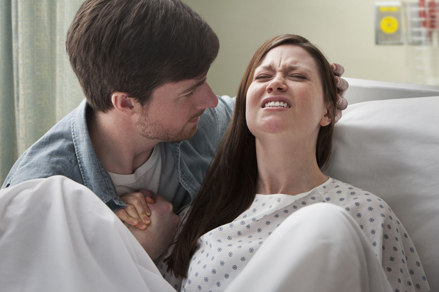 Man supporting a woman as she delivers a baby