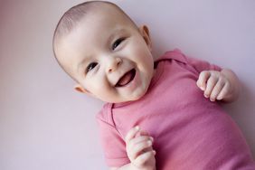 Smiling baby girl wearing a pink onesie