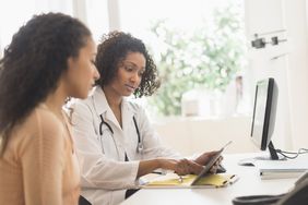 Doctor and patient using digital tablet in office