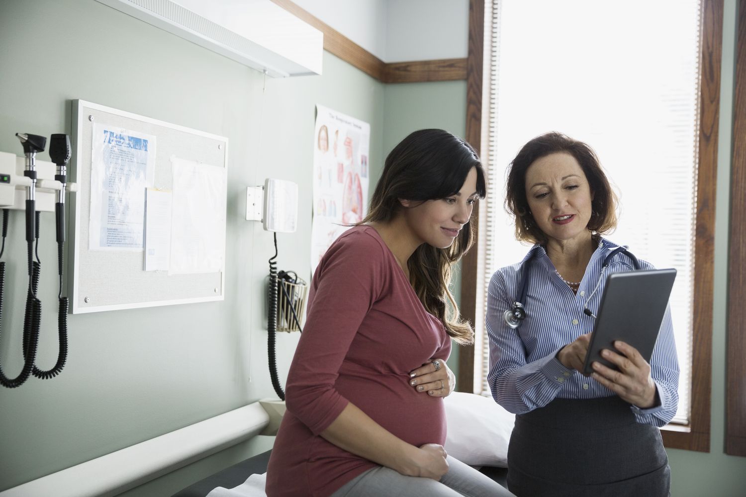 Doctor and pregnant person looking at digital tablet