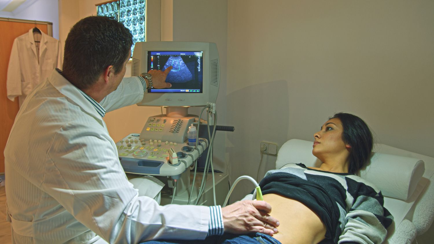 Doctor using ultrasound on pregnant person