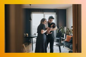 Couple holding and looking at a newborn baby in their home.