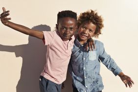 Children having joyful interaction, shot on a blue solid background on the beach in full sun