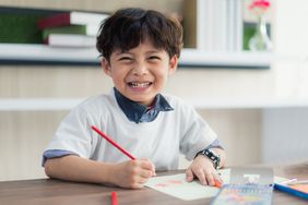 Little boy drawing with colored pencils 