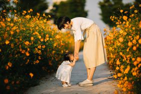 mother and baby between a row of flowers