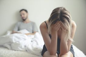 woman sitting on edge of bed upset