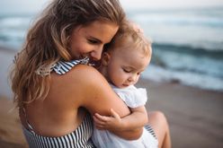 mother and toddler hugging at the beach