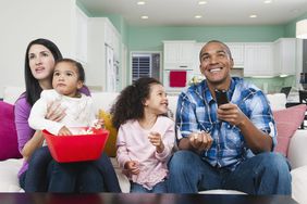 Family sitting on sofa watching television