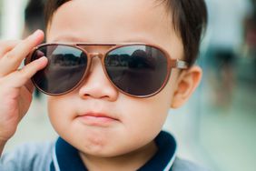 dark-haired toddler wearing oversized sunglasses