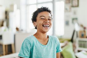 Photo of a young boy with dark curly hair and braces smiling 