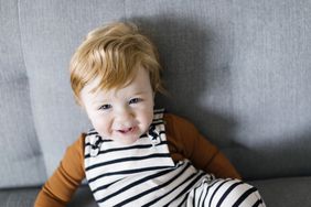 Smiling baby boy sitting on a gray couch