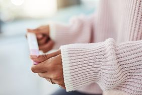 person holding pregnancy test faint positive line