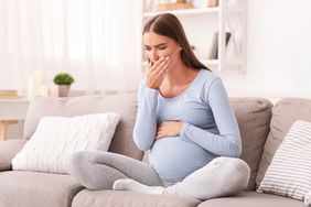 Pregnant person holding belly and coughing