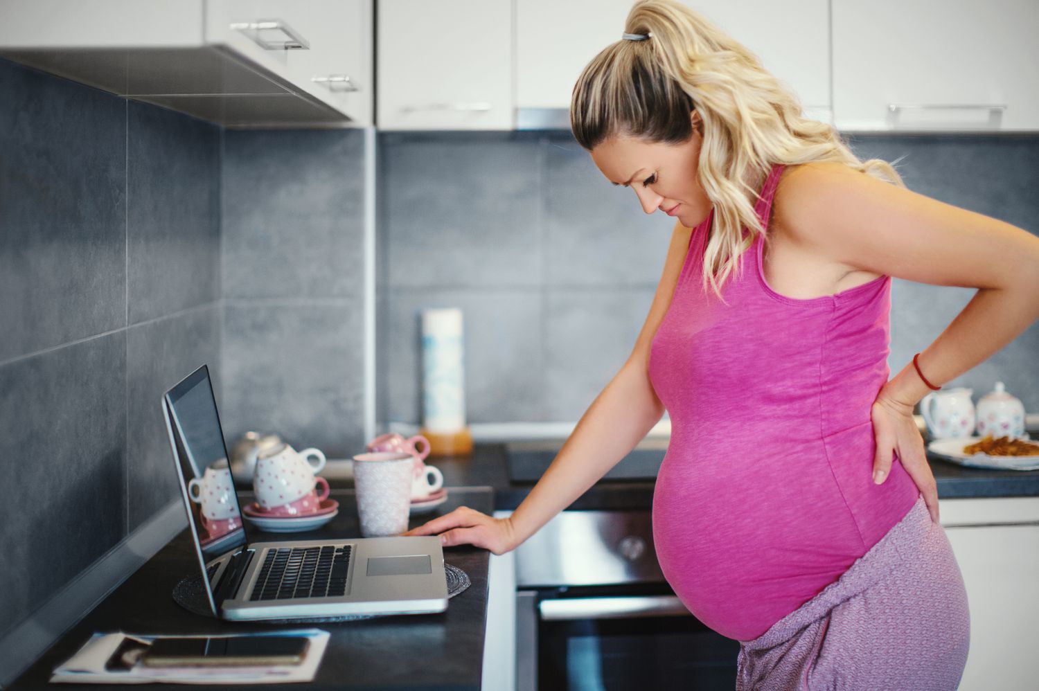 Pregnant person holding their back