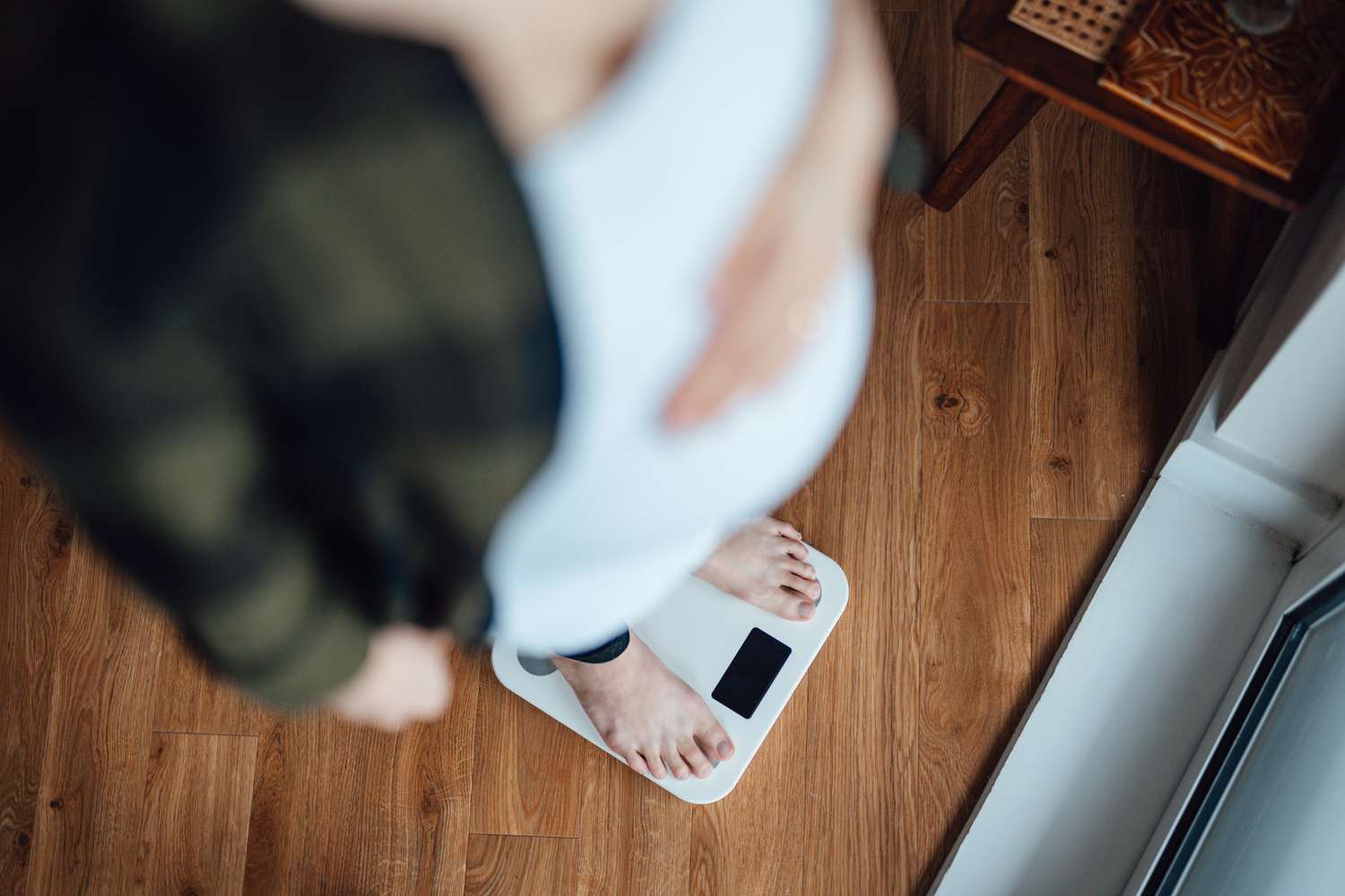 pregnant person weighing themself on a scale