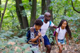 Black family, father and children, enjoy spending time together in the woods.