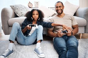 Shot of a young girl playing video games with her father at home