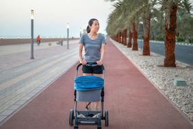 woman having a walking exercise on a running track pushing her newborn baby in the stroller