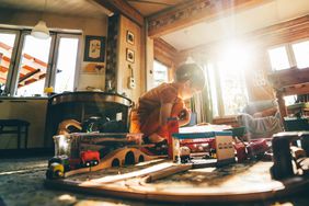 Child playing with train set in messy living room