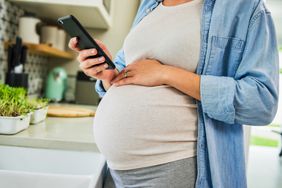 close up of a pregnant person scrolling on their phone