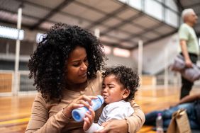 A mother feeds her crying baby with a bottle at a shelter in Brazil. 