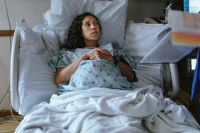 a pregnant person lying in a hospital bed and speaking with doctor