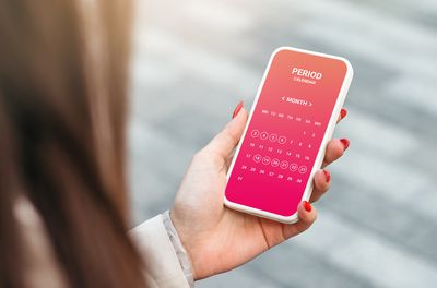 hand holding a mobile phone with a period calendar app