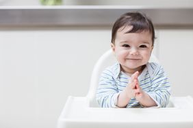 Baby boy clapping in high chair