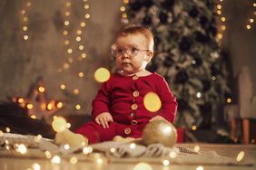 baby sitting up amid holiday decorations