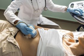 Doctor examining mature woman with ultrasound scanner device