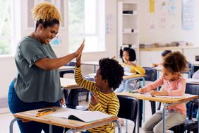 Teacher in classroom giving a student a highf ive 