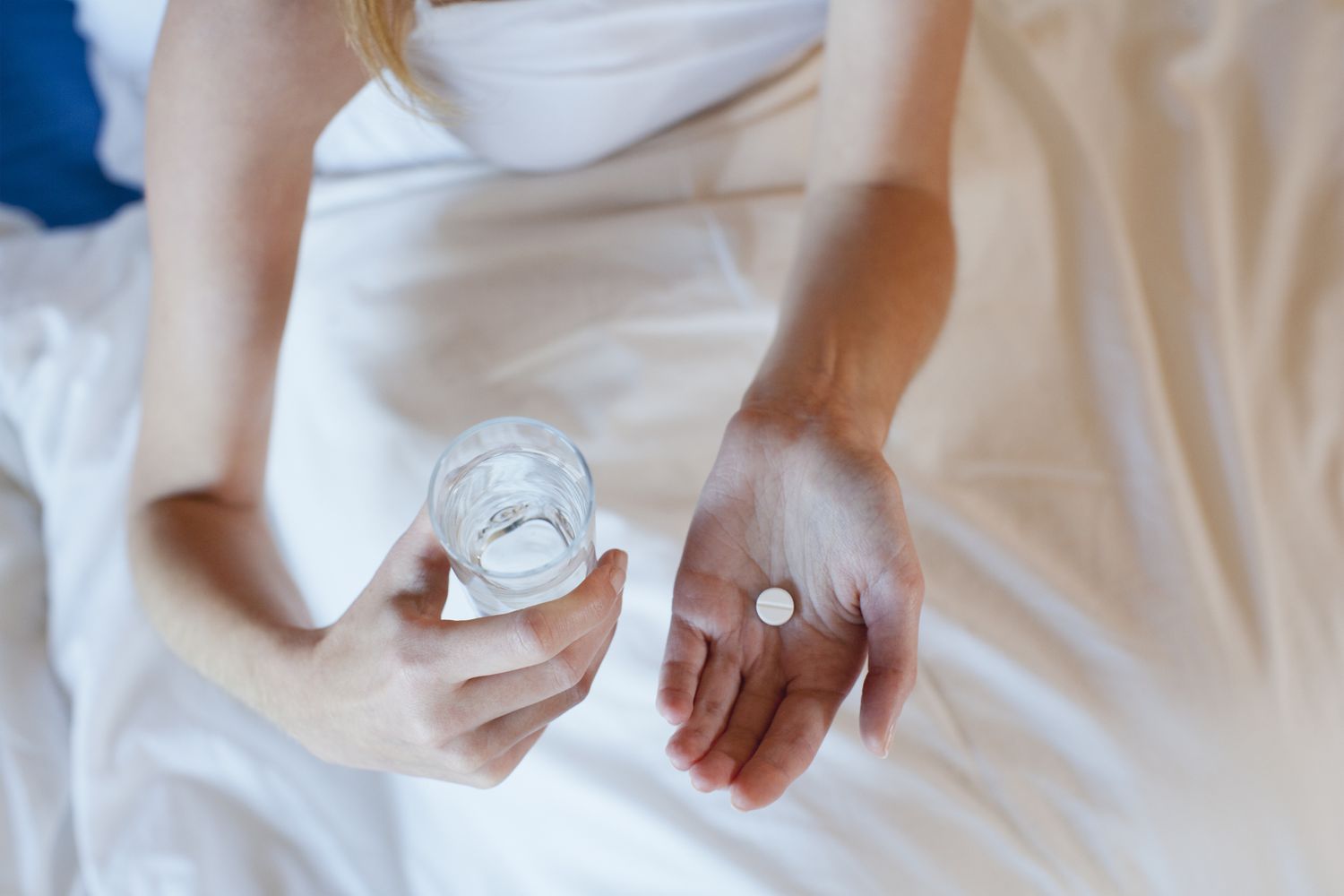 person with pill and water in hand