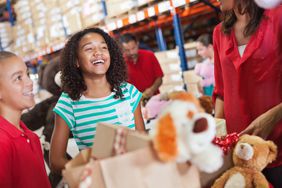 two children holding boxes donating toys 