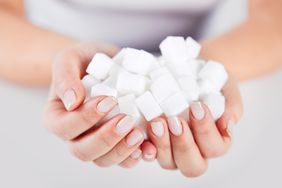 person holding cubes of sugar in their hands