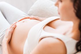 Relaxed Pregnant Woman with Hands on Bare Belly