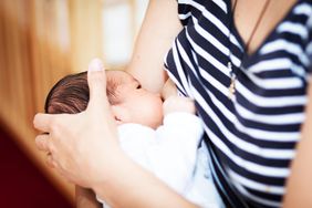 Mother breastfeeding newborn in striped shirt