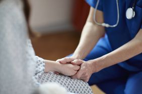 An image of a doctor holding a woman's hand.