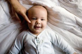 Mom touching the cheek of her smiling baby 