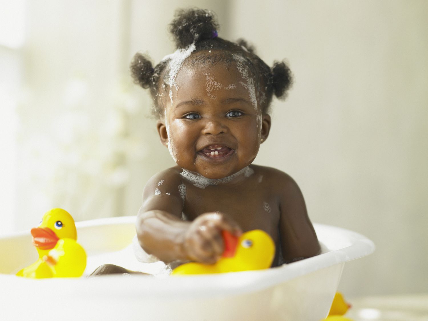 baby playing in tub with rubber ducks