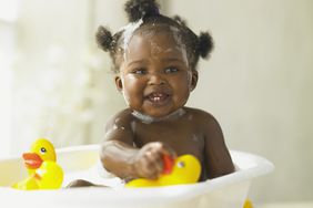 baby playing in tub with rubber ducks