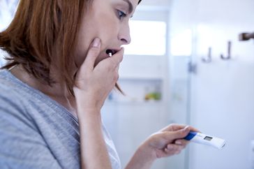 Scared woman looking at pregnancy test