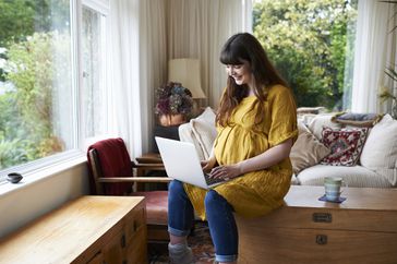 Pregnant person working on their laptop computer