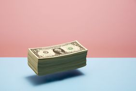 An image of a stack of money floating on a colorful background.